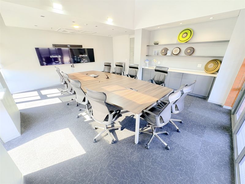 A professional boardroom featuring built-in cabinetry, floating shelving, recessed lighting, and integrated ceiling air conditioning, providing a clean and functional corporate meeting space.