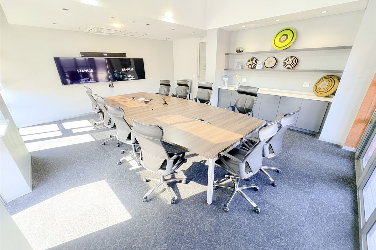 A professional boardroom featuring built-in cabinetry, floating shelving, recessed lighting, and integrated ceiling air conditioning, providing a clean and functional corporate meeting space.