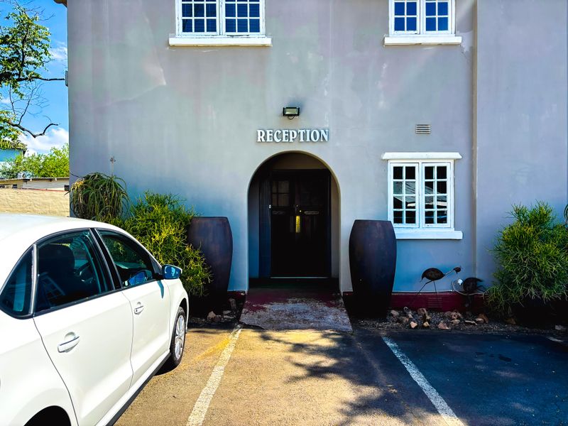 Front facade of a commercial property featuring a clearly marked reception entrance with an arched doorway and dedicated parking bay.