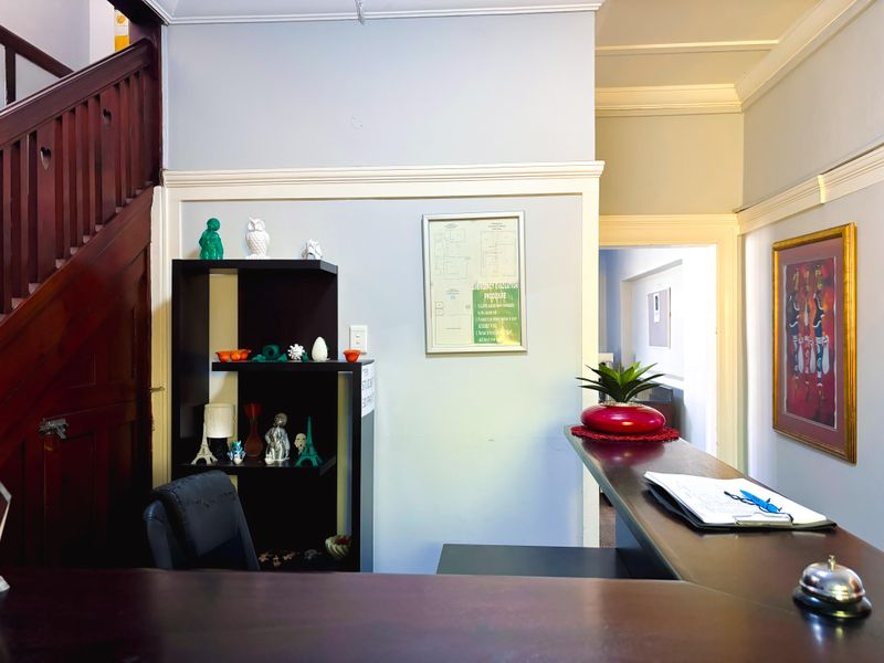 A commercial reception area featuring a timber staircase, built-in reception counter, and classic architectural detailing including crown molding and skirting boards.