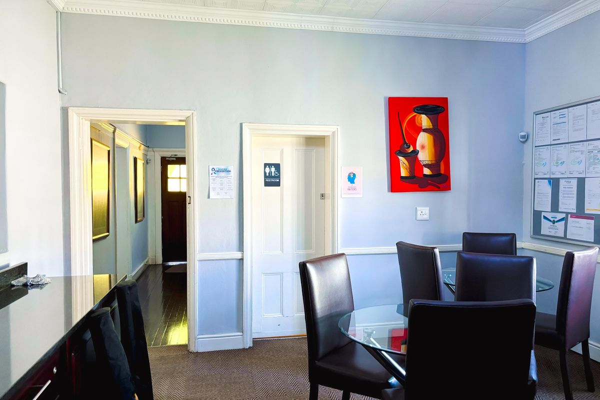 A commercial interior space featuring crown molding, wainscoting, and textured ceiling tiles, providing a functional area with access to internal hallways and restroom facilities.
