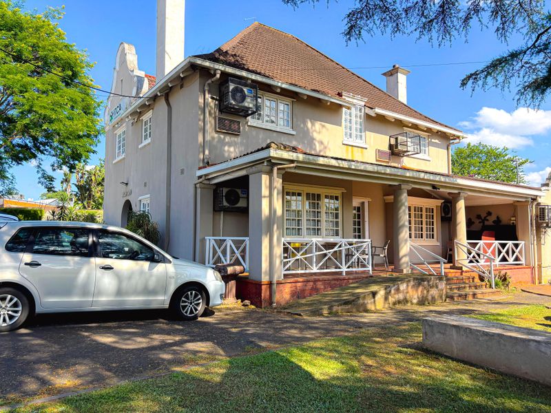 Front view of a commercial property featuring a covered veranda, tiled roof, and paved driveway access.
