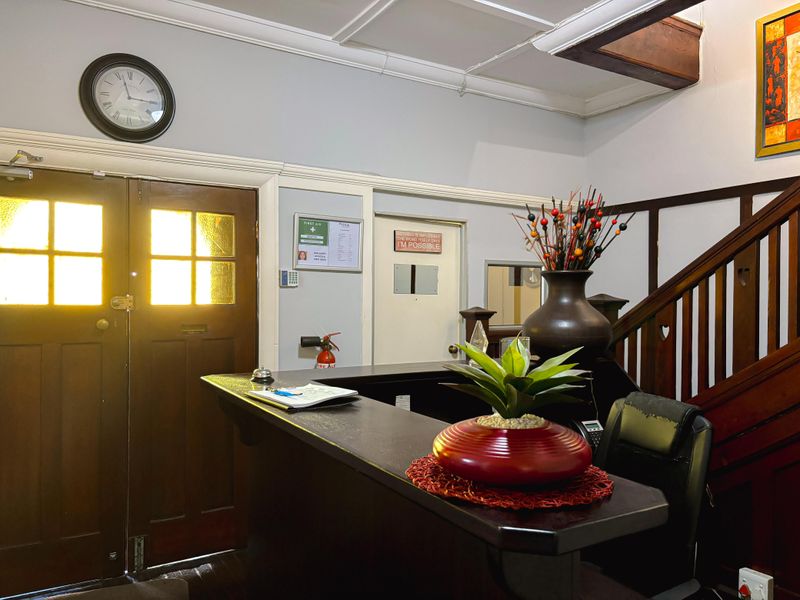 A welcoming commercial entry area featuring a built-in reception desk, timber staircase, and classic timber double doors.