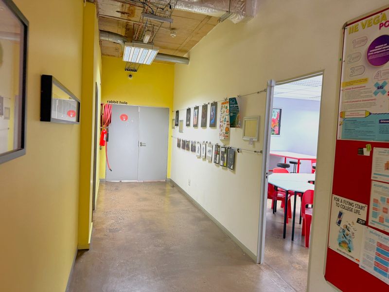A functional office hallway featuring polished concrete floors, exposed industrial ceiling elements, and a wall-mounted fire hose reel.