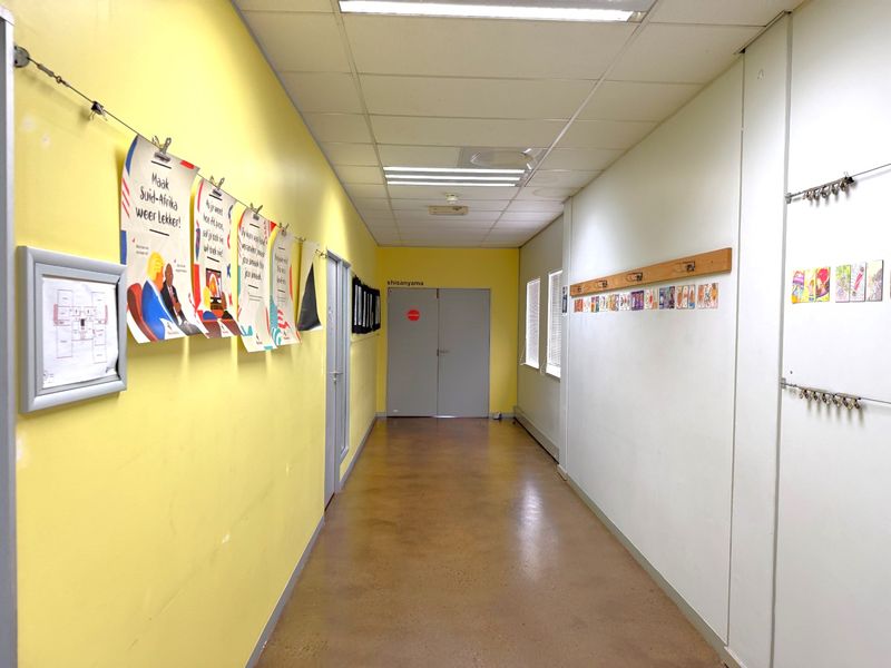A bright, functional office hallway featuring polished concrete floors, suspended ceiling tiles, and recessed lighting, providing a clean and professional circulation space.