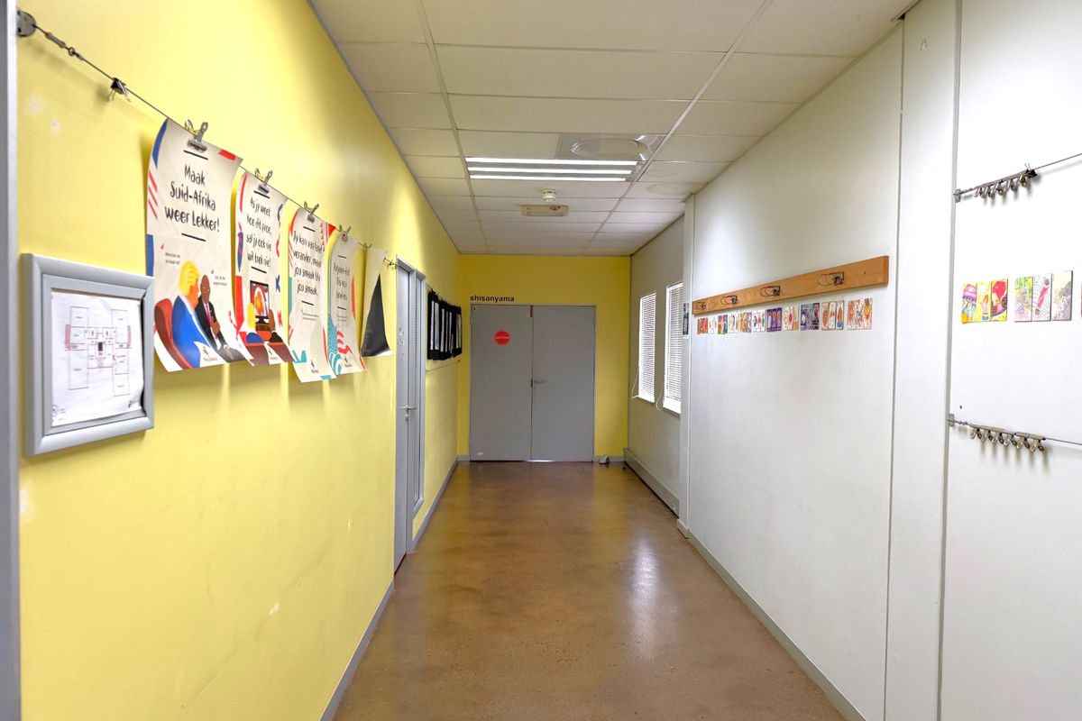 A bright, functional office hallway featuring polished concrete floors, suspended ceiling tiles, and recessed lighting, providing a clean and professional circulation space.