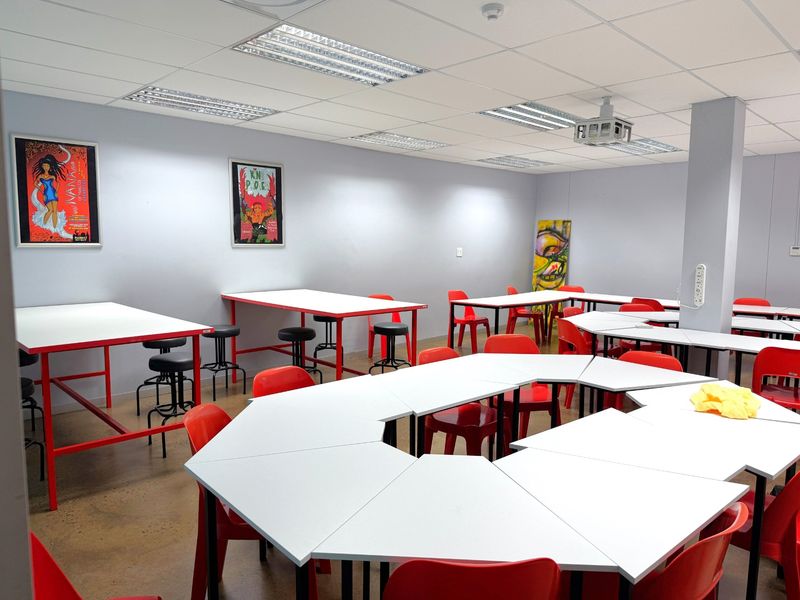 A functional office or training space featuring a suspended ceiling with recessed lighting, a ceiling-mounted projector, and polished concrete flooring.