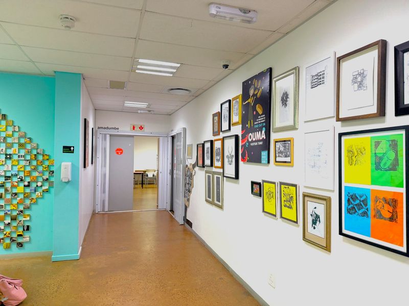 A bright office hallway featuring a suspended ceiling, recessed lighting, and a sliding door leading to an adjacent workspace.