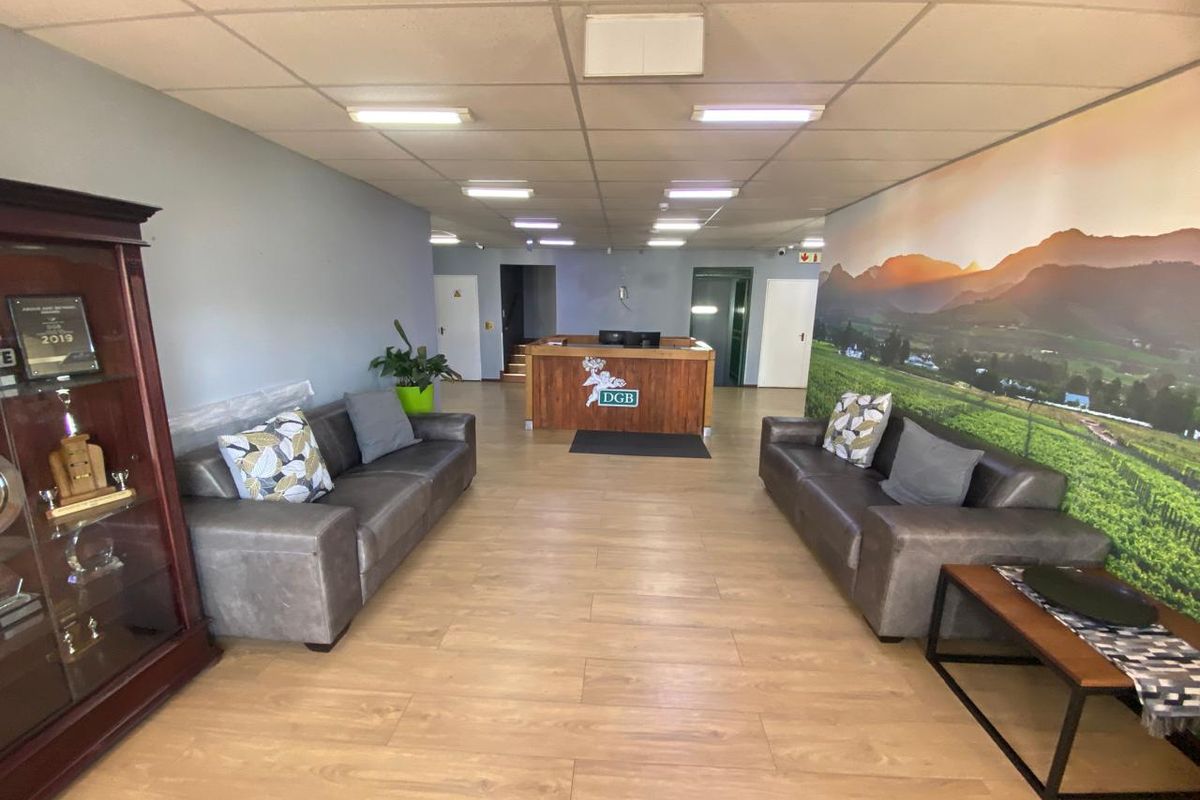 A professional industrial reception area featuring a built-in reception desk, laminate flooring, and a suspended ceiling with recessed lighting.