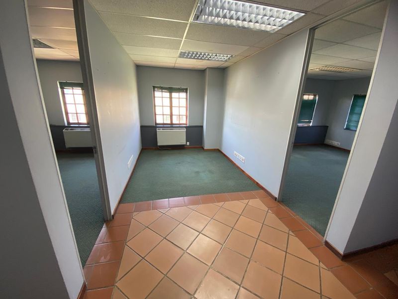 Empty office space featuring a mix of tiled and carpeted flooring, suspended ceilings with recessed lighting, and wall-mounted HVAC units.