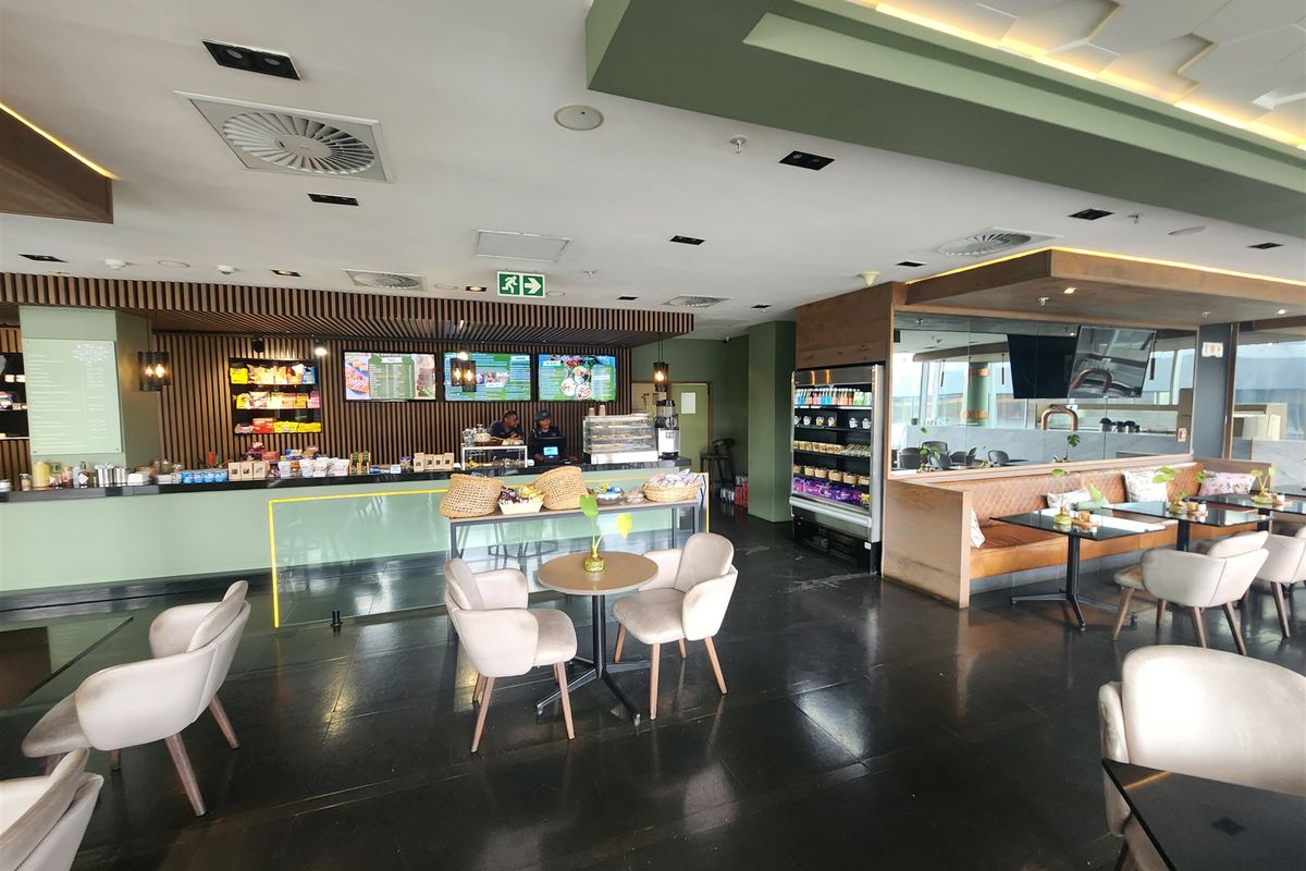 A modern, well-maintained open-plan office cafe area featuring a service counter, built-in booth seating, and sophisticated coffered ceiling lighting.