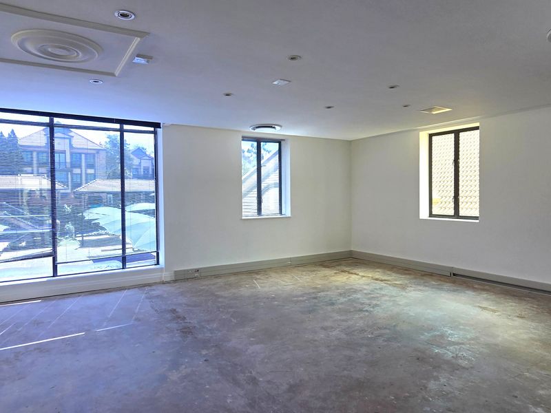 An empty office space featuring recessed lighting, aluminium-framed windows, and unfinished concrete flooring, offering a blank canvas for custom interior fit-outs.