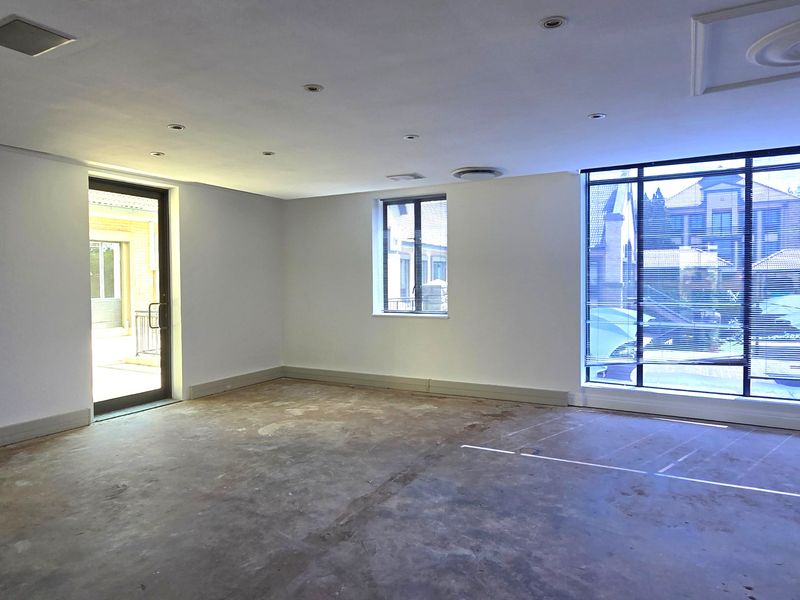 A spacious, empty office area featuring large windows, recessed lighting, and an unfinished concrete floor, ready for custom flooring installation.
