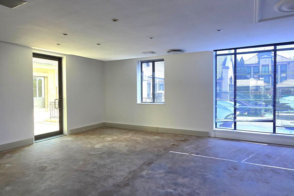 A spacious, empty office area featuring large windows, recessed lighting, and an unfinished concrete floor, ready for custom flooring installation.