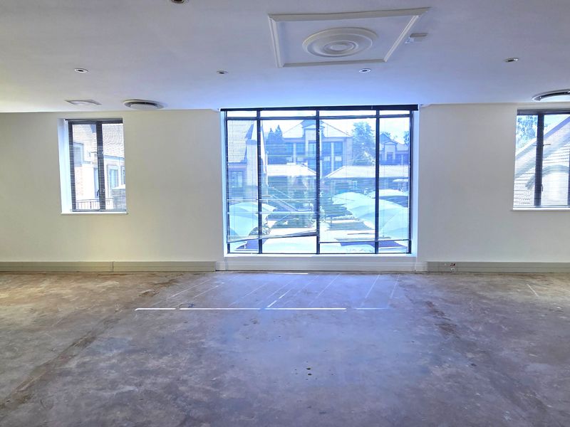 Spacious, empty office area featuring large windows with blinds, recessed ceiling lighting, and unfinished concrete flooring, ready for custom fit-out.