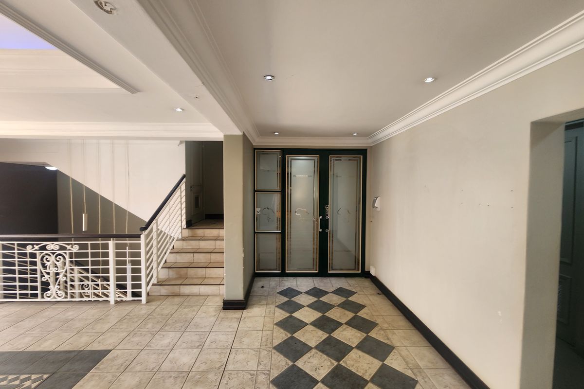 Spacious office entrance foyer featuring decorative crown molding, recessed lighting, a tiled floor with a diamond pattern inlay, and a wrought iron staircase.