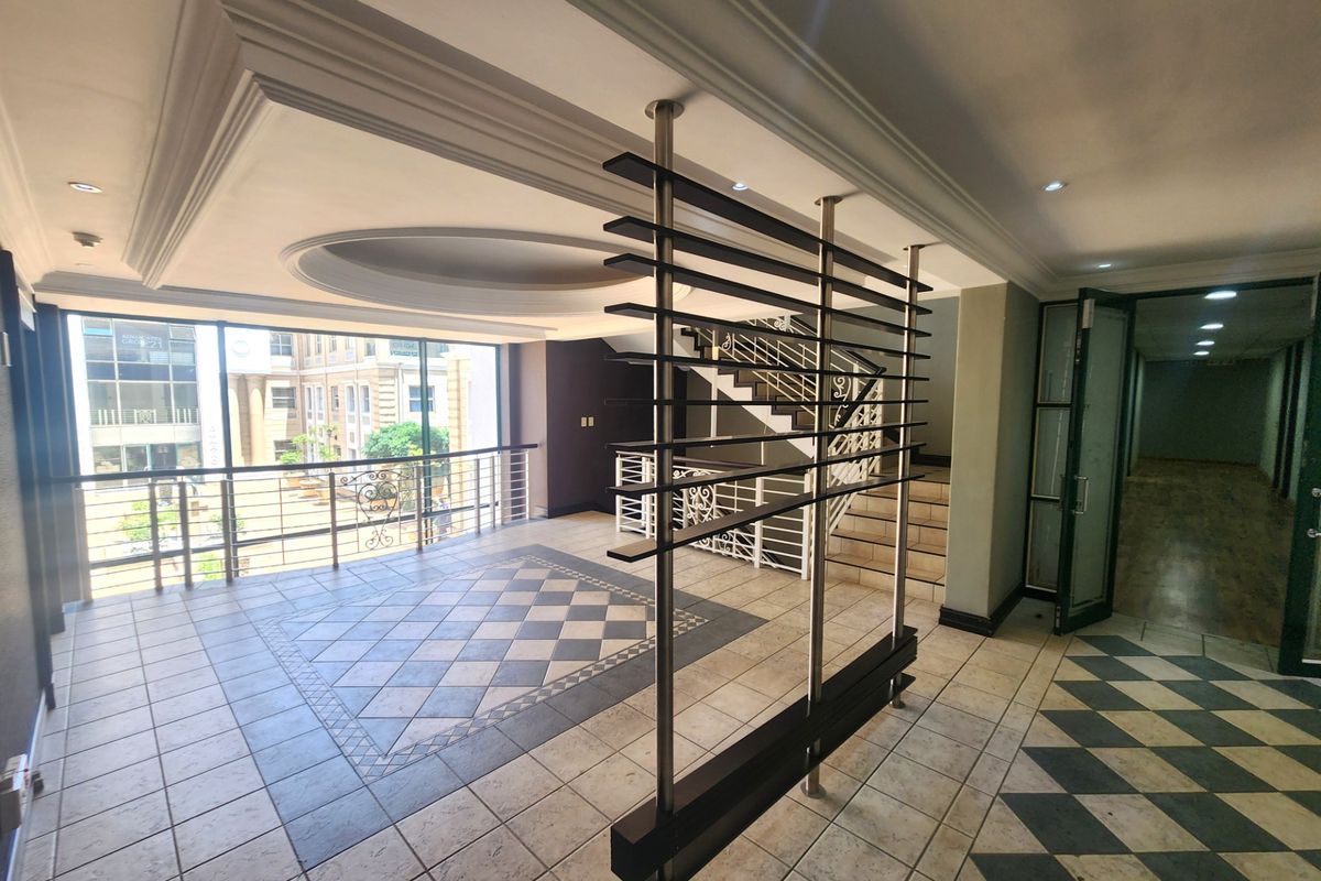 Spacious office lobby area featuring decorative ceiling details, tiled flooring, and a modern metal partition, providing an open and professional atmosphere.