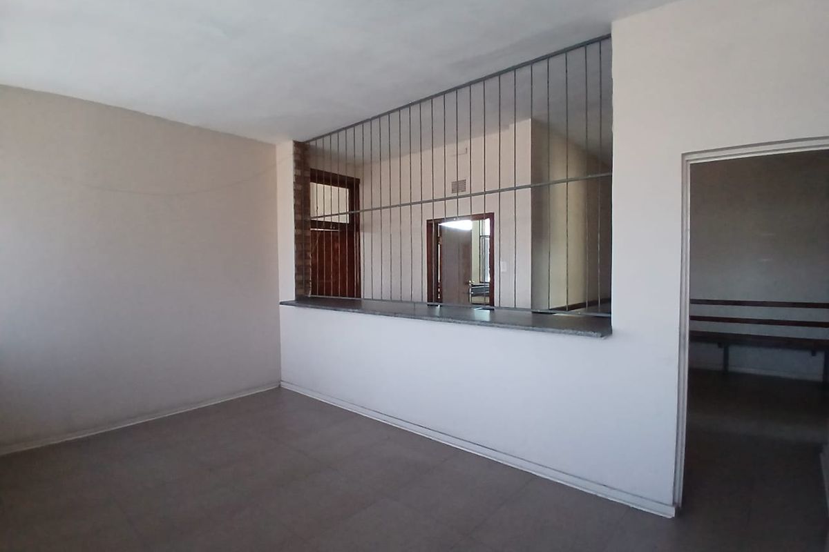 Empty office space featuring a service counter with a security grille, tiled flooring, and neutral wall finishes.