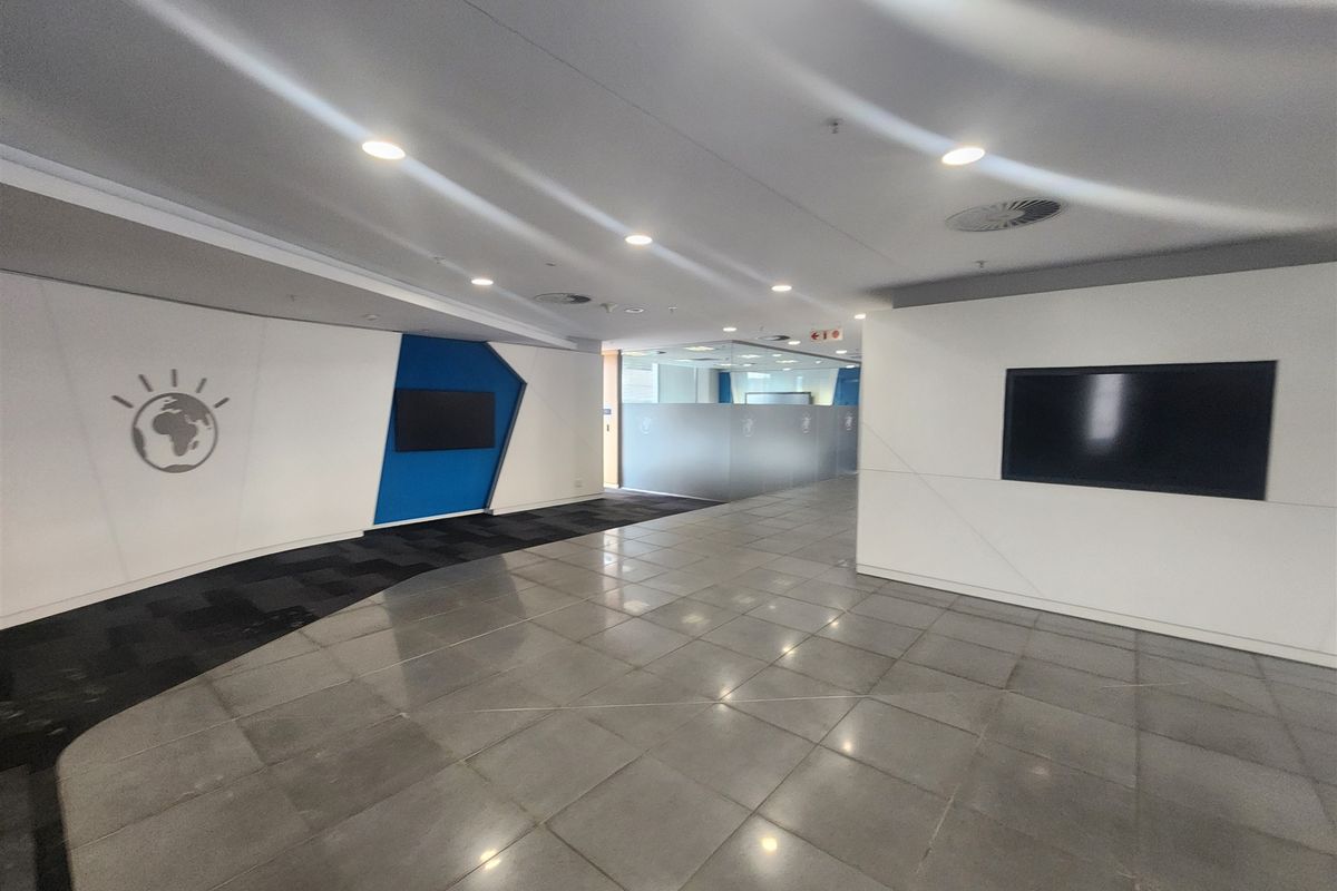 A modern, spacious office lobby or reception area featuring clean lines, professional glass partitioning, and a combination of tiled and carpeted flooring.