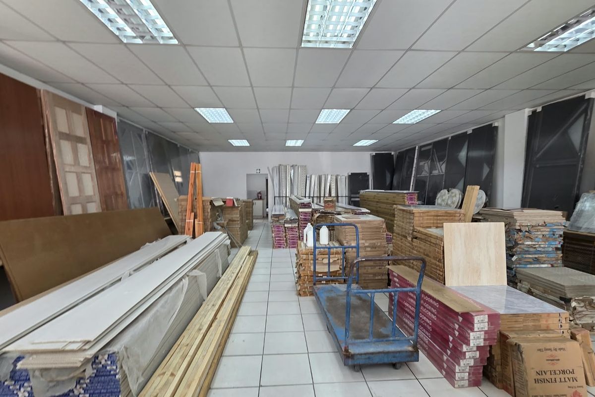 A commercial utility or storage space featuring a suspended ceiling with recessed lighting and tiled flooring, currently utilized for inventory storage.