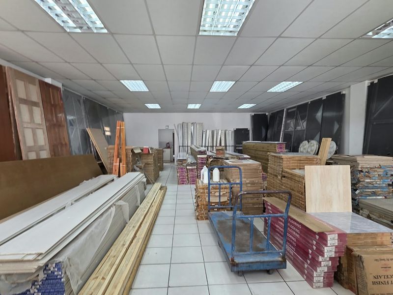 A commercial utility or storage space featuring a suspended ceiling with recessed lighting and tiled flooring, currently utilized for inventory storage.