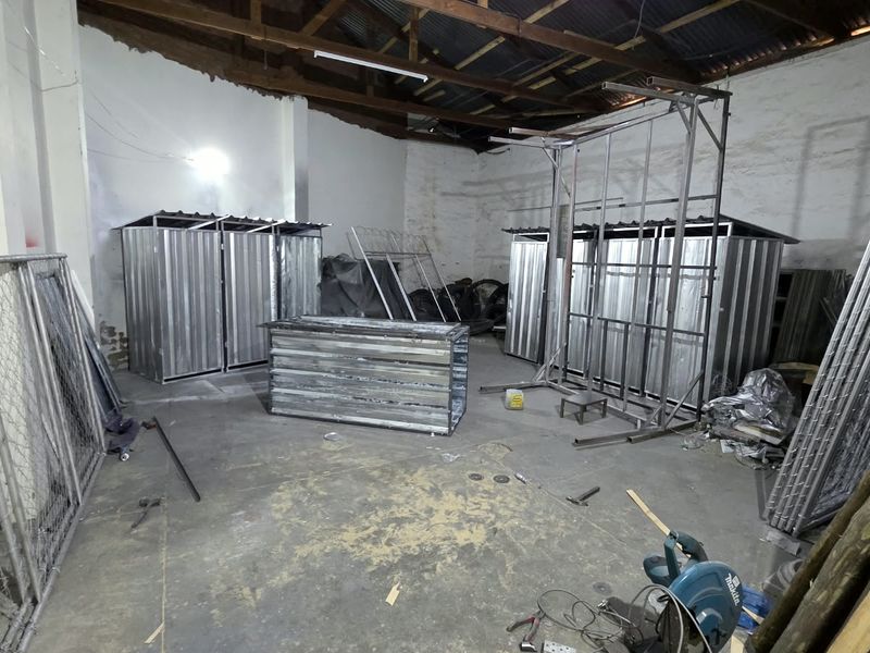 An industrial utility space featuring exposed timber roof trusses, concrete flooring, and metal wall structures, suitable for storage or workshop use.