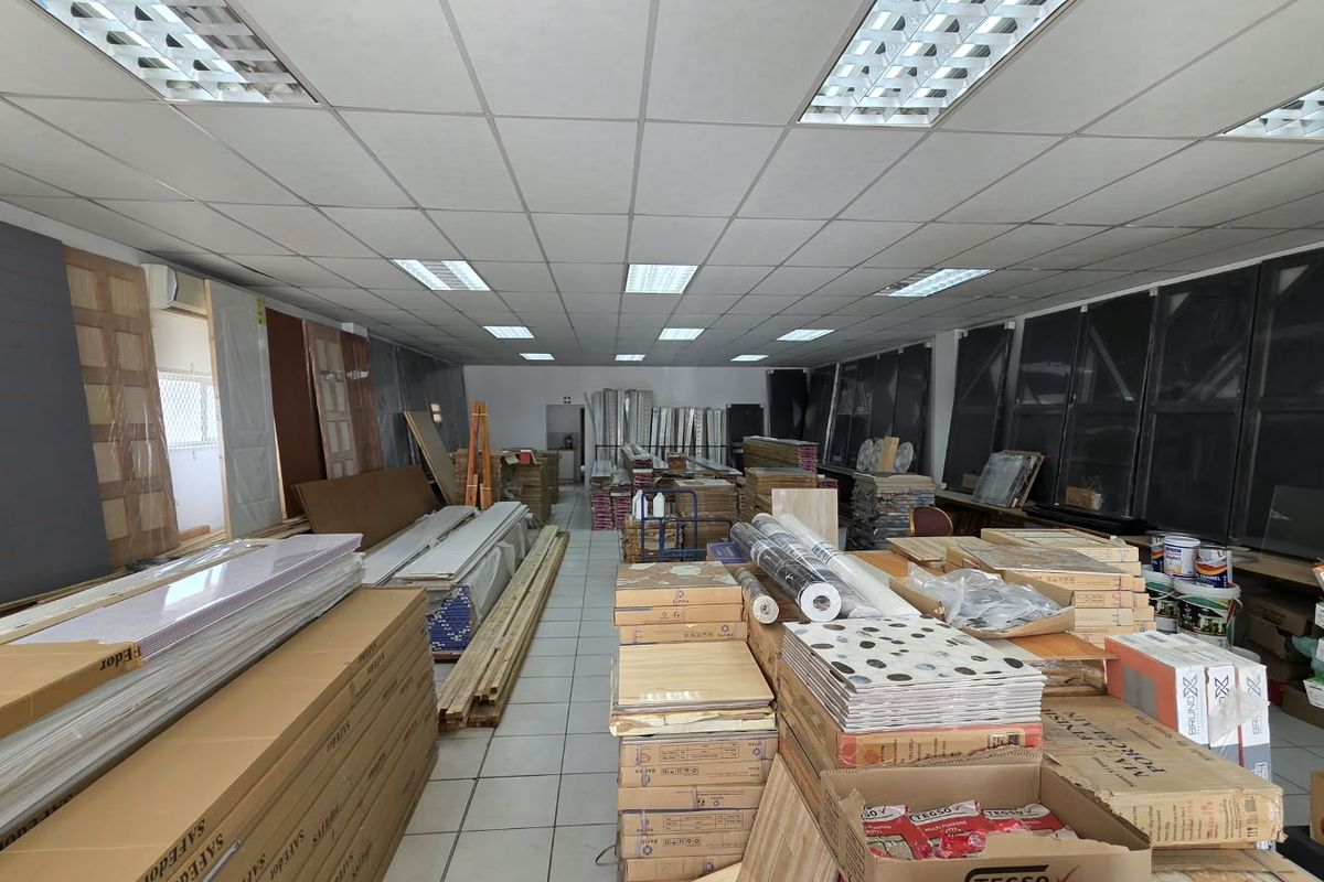 A commercial utility or storage space featuring a suspended ceiling with recessed lighting and tiled flooring, currently utilized for inventory storage.