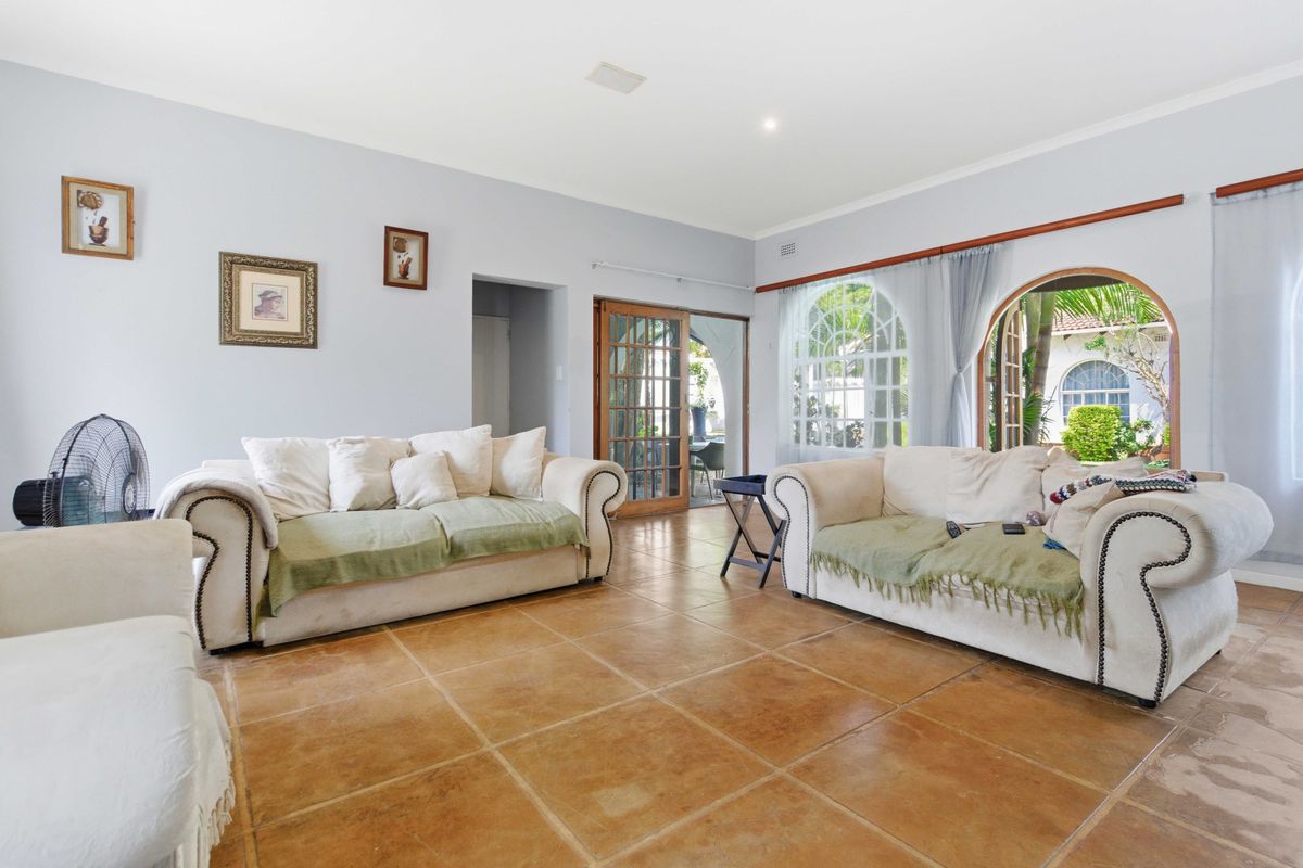 Spacious living room featuring terracotta floor tiles, arched windows, and french doors providing access to the outdoor area.