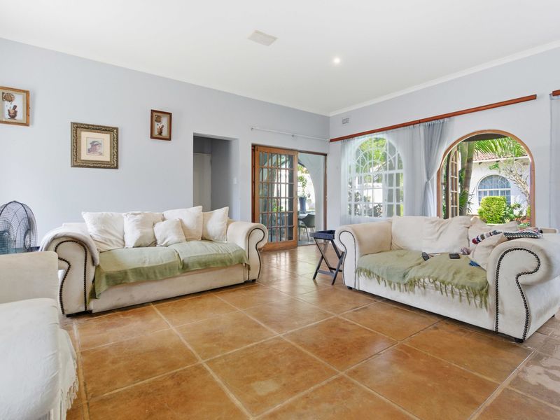 Spacious living room featuring terracotta floor tiles, arched windows, and french doors providing access to the outdoor area.