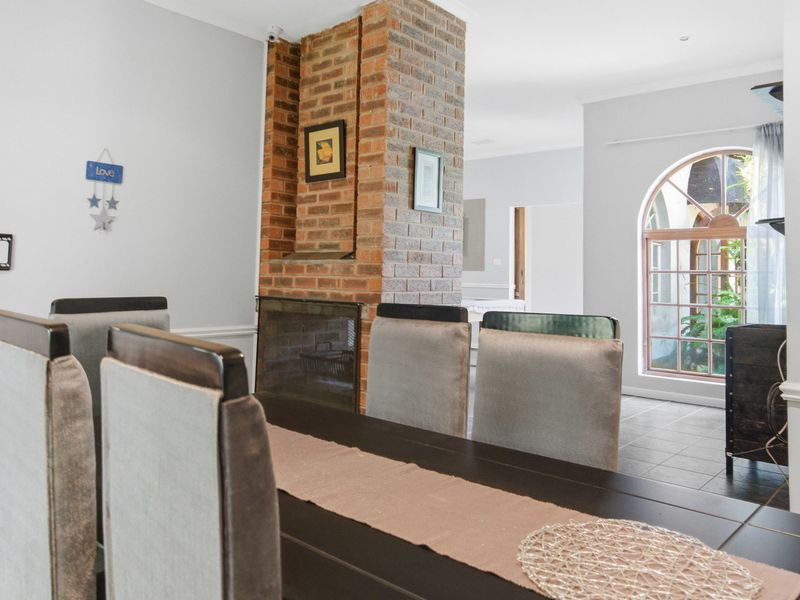 Dining room featuring an exposed brick fireplace, arched window, and tiled flooring, creating a warm and inviting space for meals.