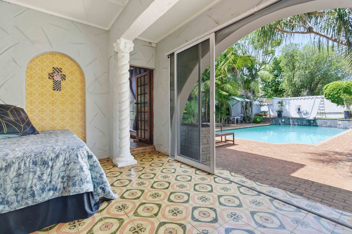 Bedroom featuring decorative tiled flooring, a classic column, and sliding glass doors opening directly onto a private pool area.