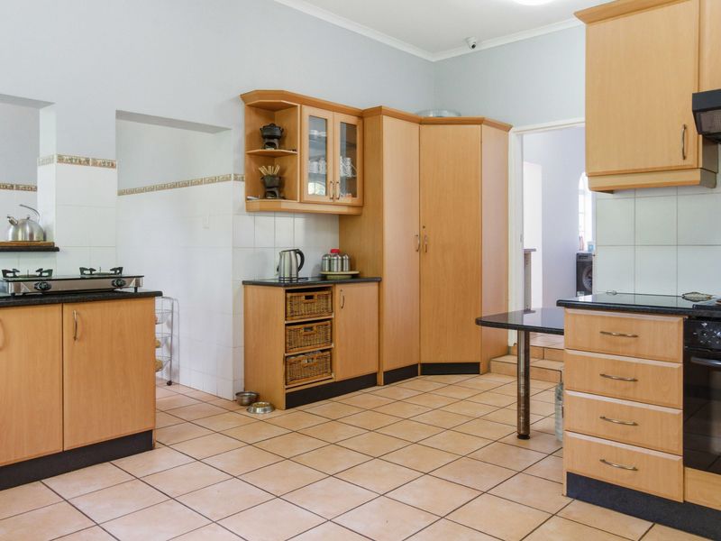 Spacious kitchen featuring light wood cabinetry, granite countertops, built-in oven, gas hob, and tiled flooring with a functional layout.