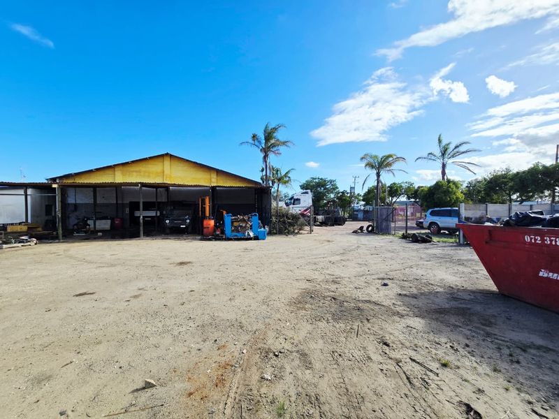 Industrial property featuring a large warehouse structure with an expansive open yard area, suitable for storage or logistics operations.
