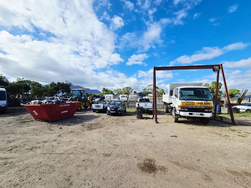 An industrial yard featuring an unpaved surface and a fixed gantry crane structure, suitable for heavy equipment storage or industrial operations.