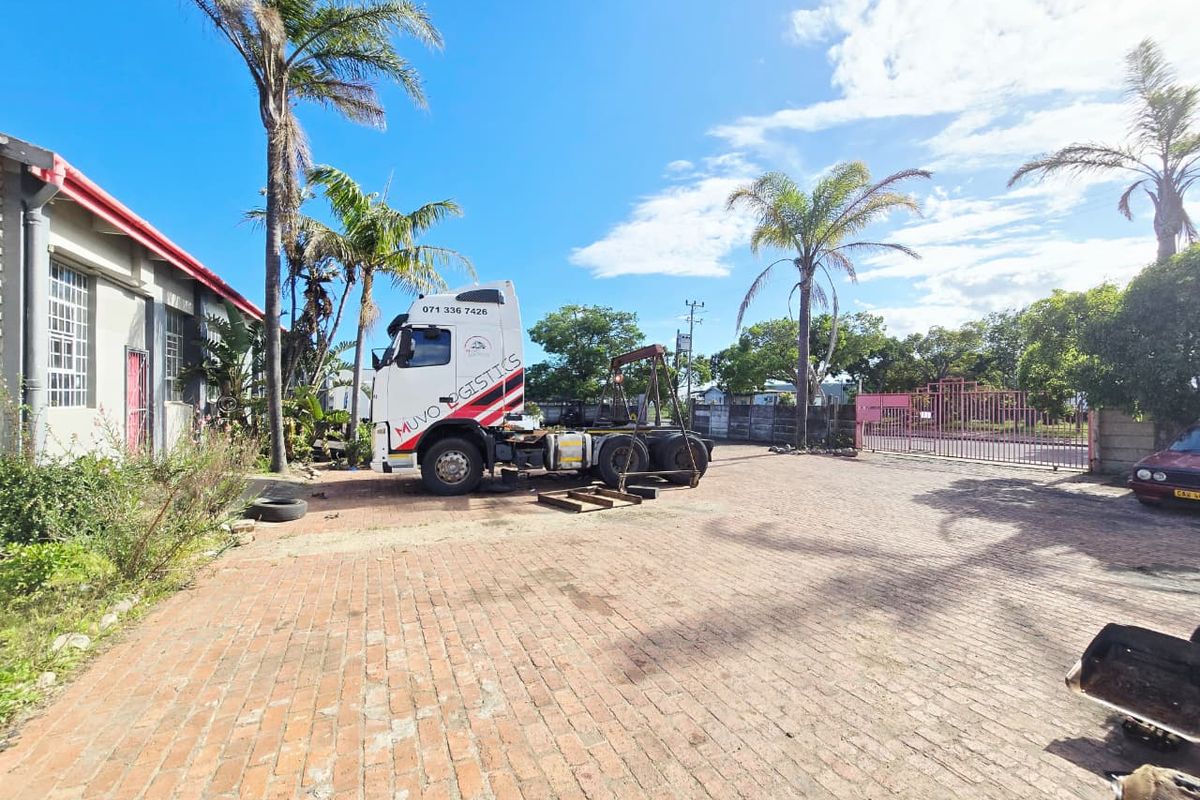 Industrial property exterior featuring a large brick-paved yard, perimeter fencing, and access gate, suitable for logistics or commercial operations.