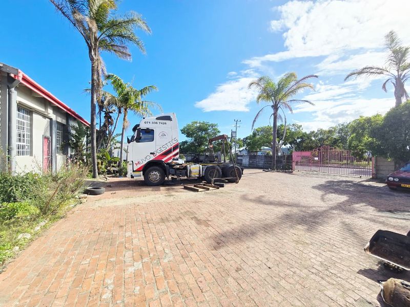 Industrial property exterior featuring a large brick-paved yard, perimeter fencing, and access gate, suitable for logistics or commercial operations.