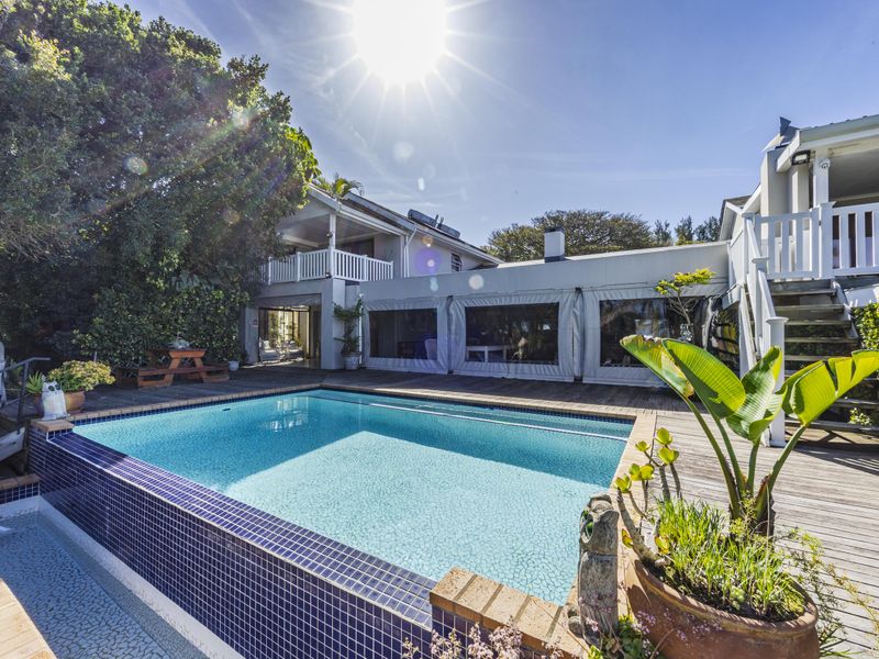 Outdoor pool area featuring a tiled swimming pool, timber decking, and an elevated balcony with an external staircase.