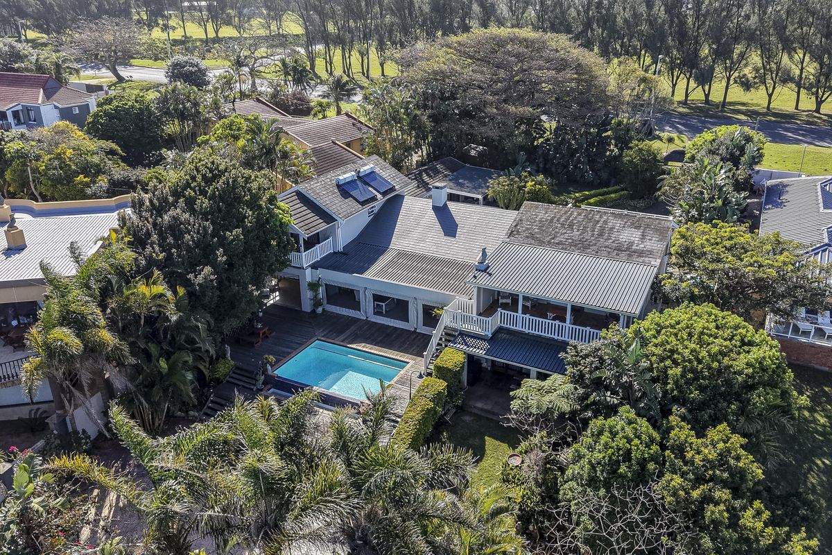 Aerial view of the guest house property featuring a swimming pool, wooden decking, and a multi-level structure with metal roofing and solar panels.