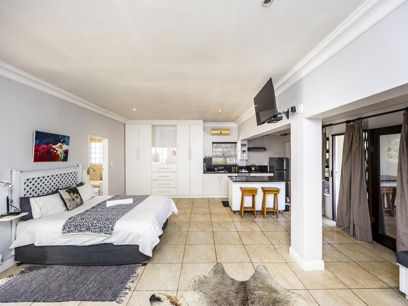 Spacious open-plan guest suite featuring a bedroom area, integrated kitchenette with island, and direct access to an outdoor patio space.