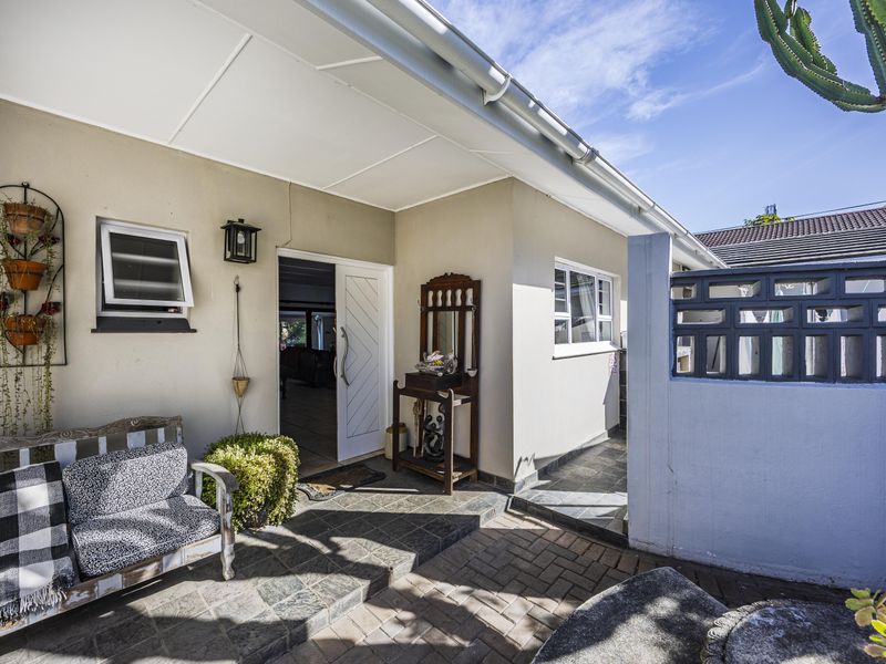 A covered patio area featuring slate tile flooring, brick paving, and a decorative breeze block wall, providing a welcoming entrance to the guest house.