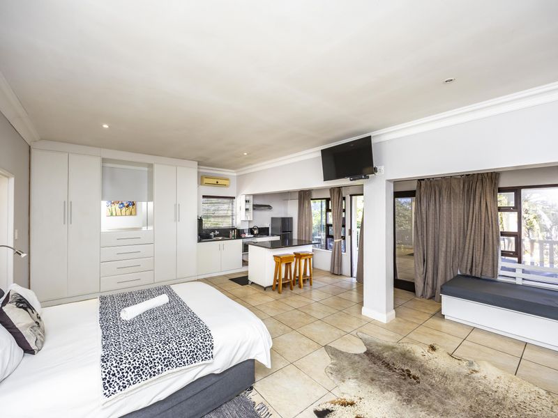 Spacious open-plan bedroom and kitchen area featuring built-in cabinetry, tiled flooring, and direct access to an outdoor patio through sliding glass doors.