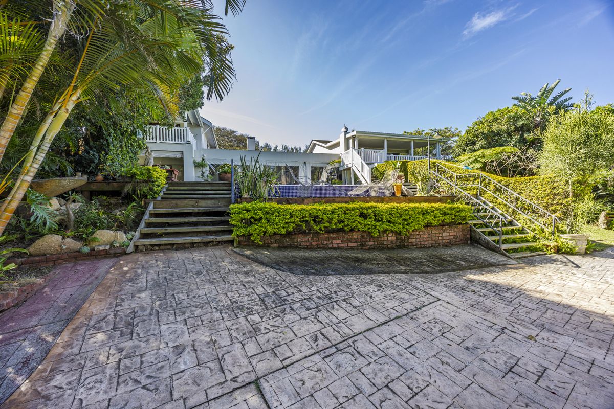 Rear exterior view featuring a swimming pool, tiered garden, brick retaining walls, and access staircases leading to the main dwelling.