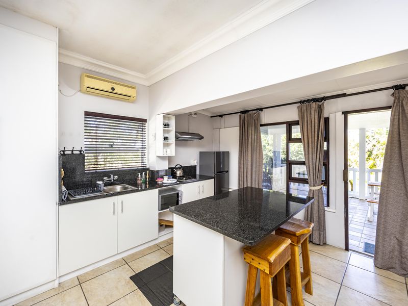 A functional kitchen featuring granite countertops, white cabinetry, and tiled flooring, with direct access to an outdoor patio area.