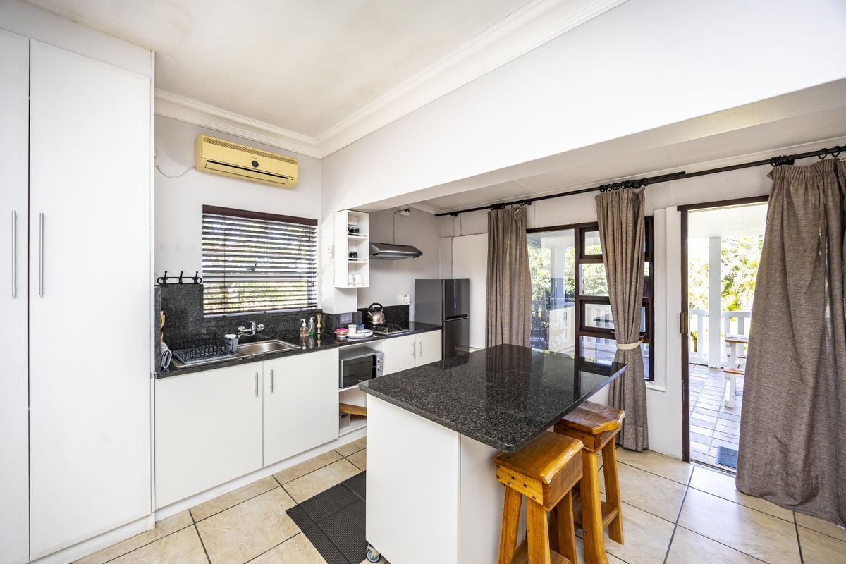 A functional kitchen featuring granite countertops, white cabinetry, and tiled flooring, with direct access to an outdoor patio area.
