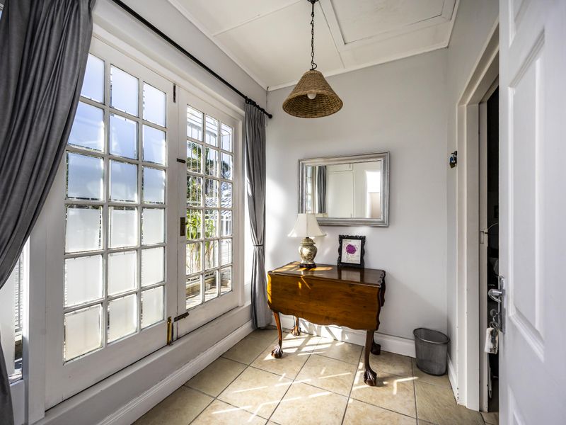 A bright entrance area featuring tiled flooring and classic French doors that provide natural light and access to the exterior.