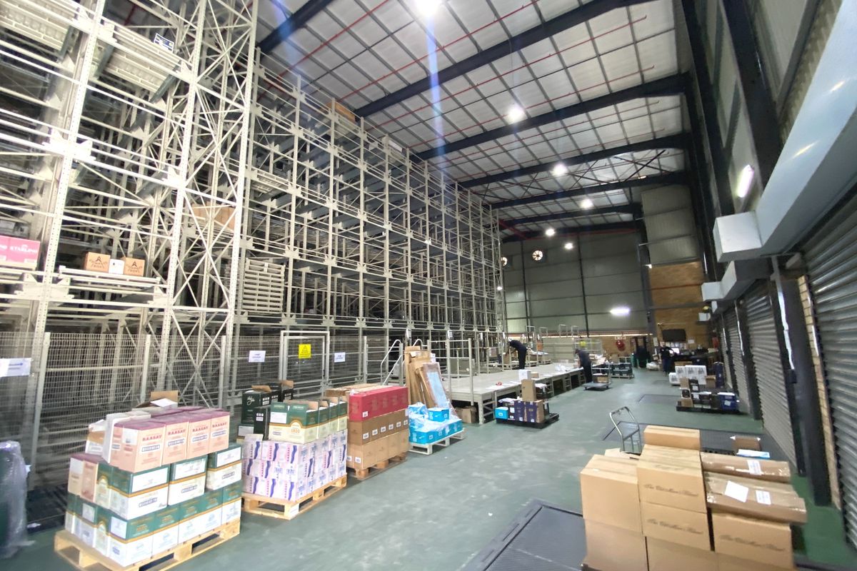 Spacious industrial warehouse featuring high-bay racking systems, exposed steel roof structure, and durable concrete flooring, suitable for large-scale storage and logistics operations.