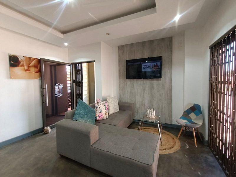 A modern reception or waiting area featuring polished concrete floors, a recessed ceiling with downlights, and a textured feature wall.