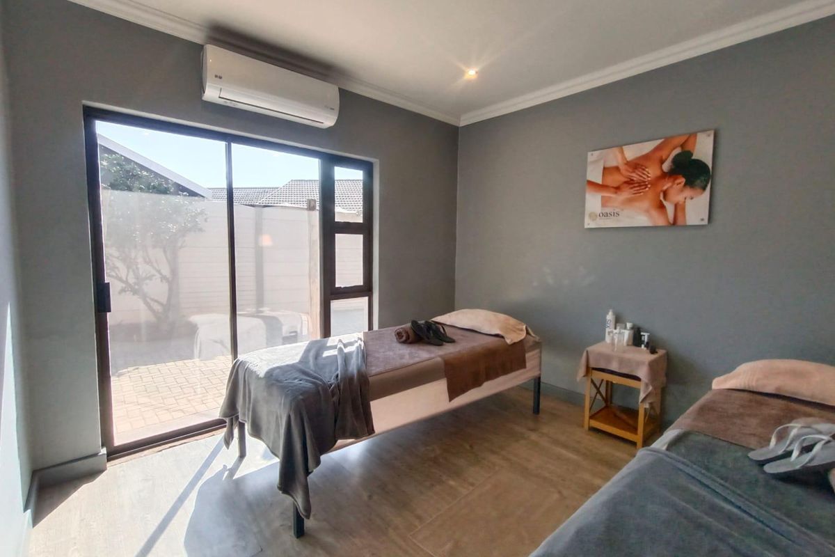 A well-maintained treatment room featuring laminate flooring, a split-system air conditioner, and a large sliding glass door providing natural light.