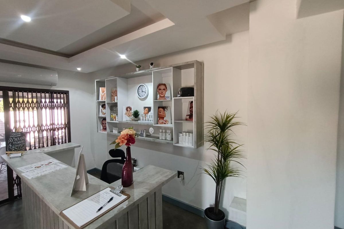 A professional reception area featuring a custom built-in service desk, integrated display shelving, recessed ceiling lighting, and a secure entrance.