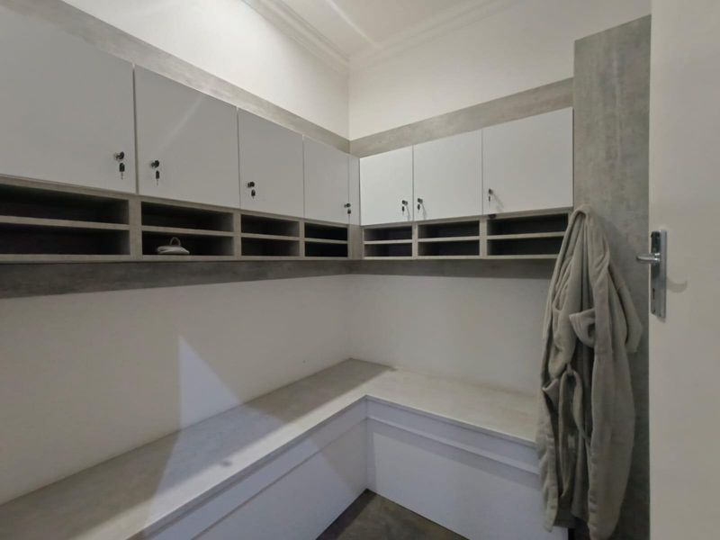 A functional utility space featuring built-in cabinetry, storage lockers, and integrated bench seating with a clean, modern finish.